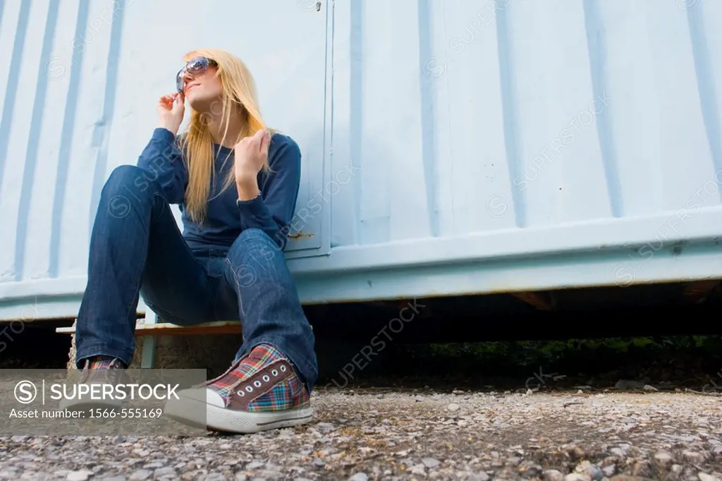Attractive young woman is sitting by the light Blue wall