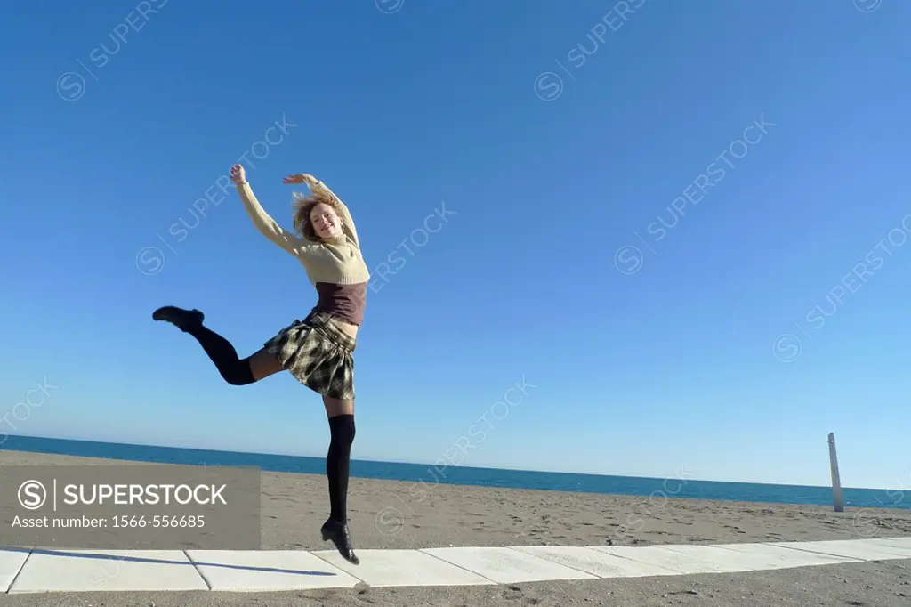 Woman jumping in Torremolinos beach, Malaga province, Andalusia, Spain