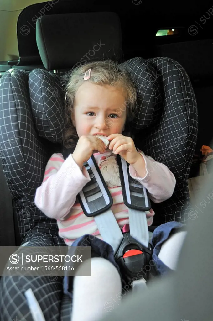 child, girl, 2 years old, sits in a car in an infant carrier