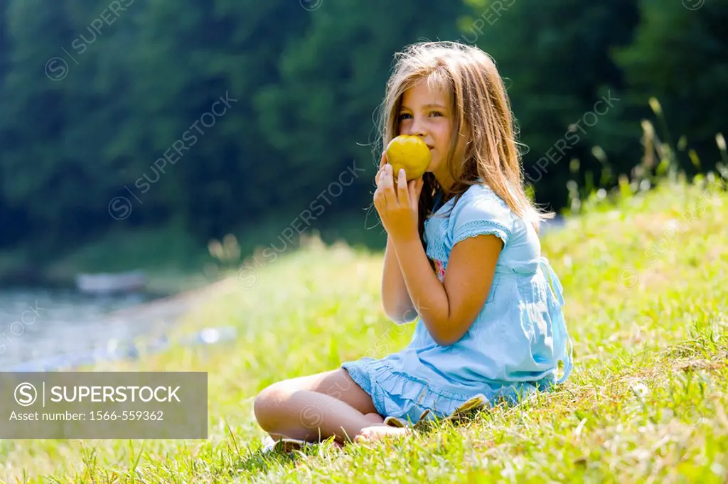 Six year old girl is eating a pear