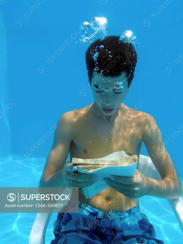 13 years old boy reading underwater