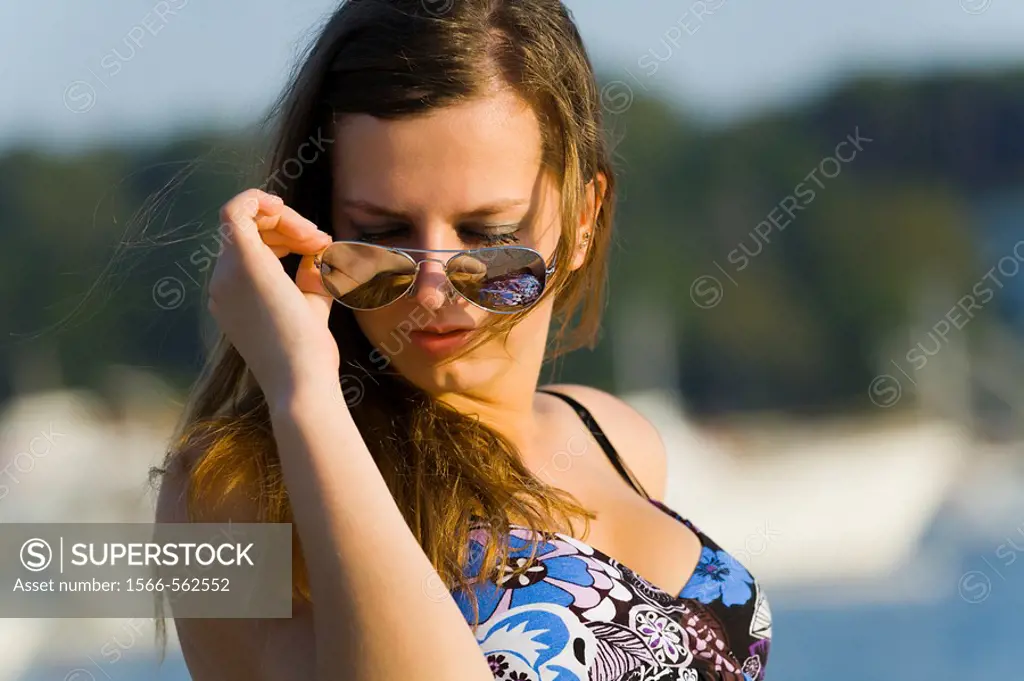 Putting on sunglasses young woman portrait