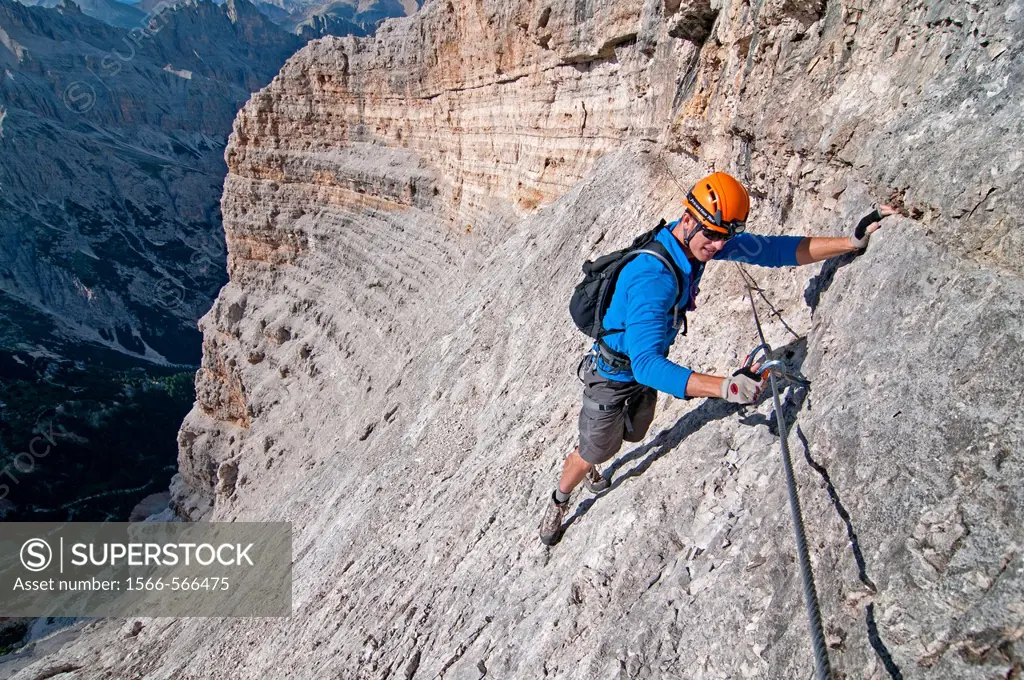 Man climbing the Giovanni Lipella via ferrata on Tofana De Rozes in the Dolomite Mountains near the city of Cortina in northern Italy