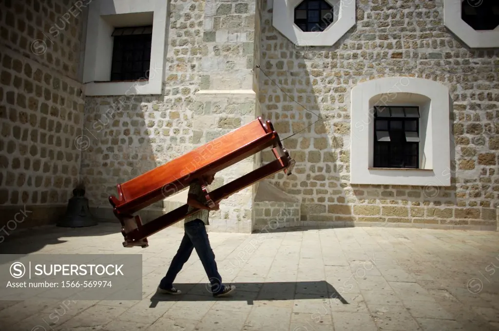 A man carries a church bench to the Basilica de la Soledad, or Solitude Basilica, after a holy week procession in Oaxaca, Mexico