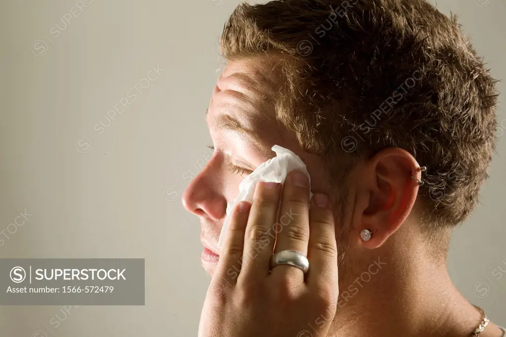 Young man wiping his face with a paper towel