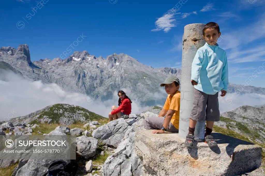 Family in the summit of Peña Maín next to a gedesic vertex, Urrieles massif, in the Picos de Europa National Park, Asturias, Spain