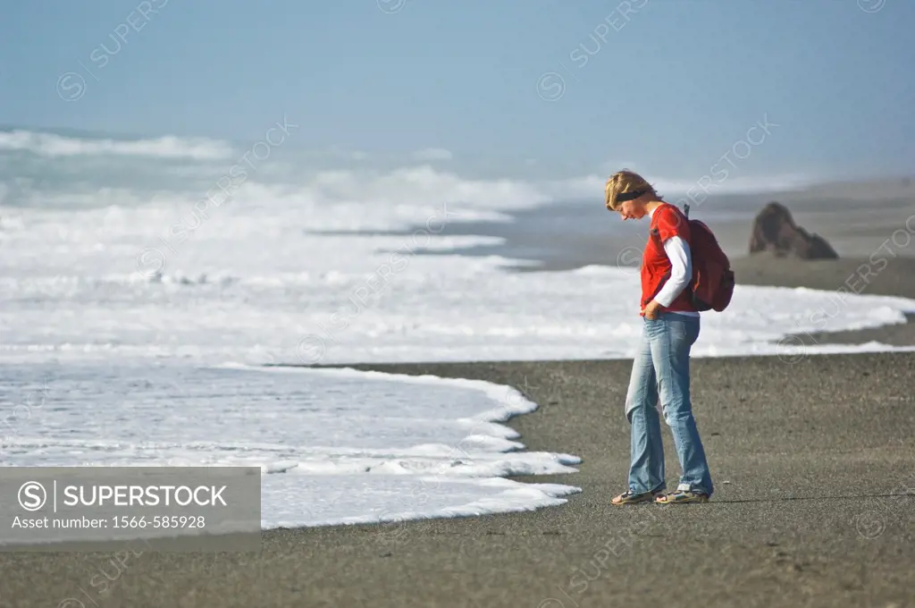 woman watching incoming waves on empty beach