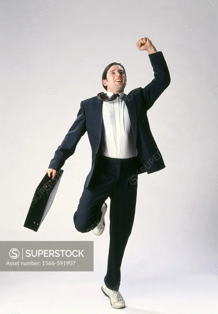 Studio image of businessman in suit and runners triumphantly finishing his race