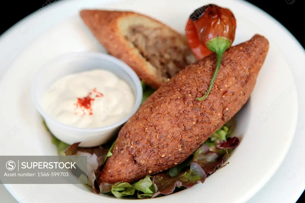 A serving of Kibbeh also kubbeh with Tehina and salad  Kibbeh is meat and spices wrapped in bulgur and deep fried