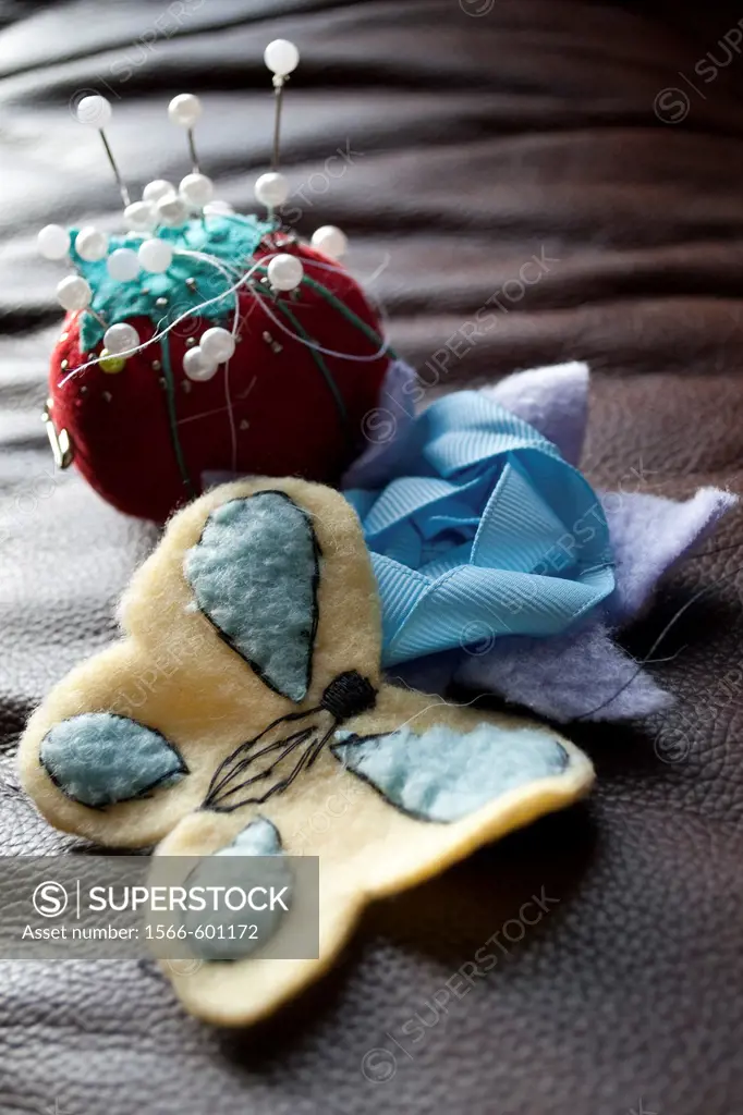 A tomato pin cushion and a flower and butterfly sewn by hand