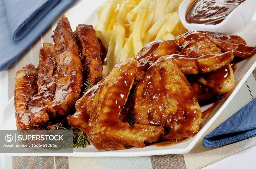 Meat platter with marinated chicken wings and ribs with sauce and chips, food