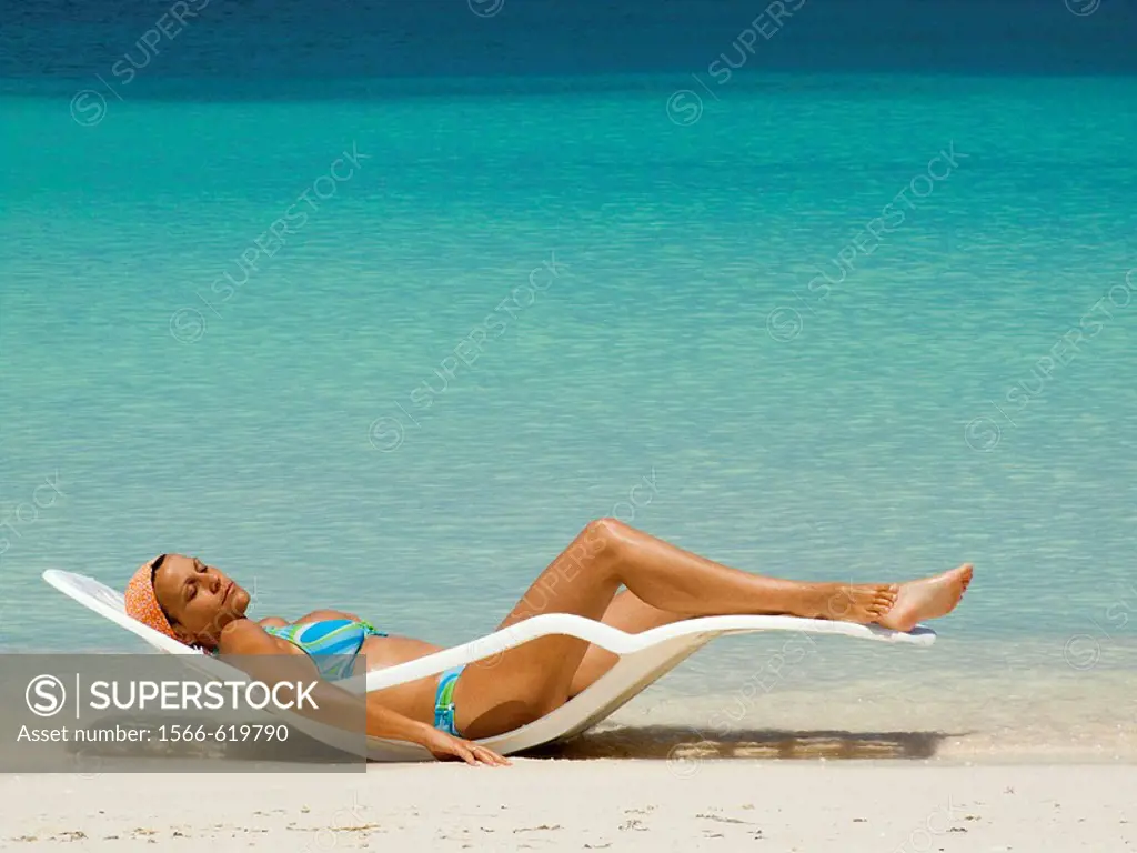 Girl in hammock taking sun bath on a Caribbean beach.