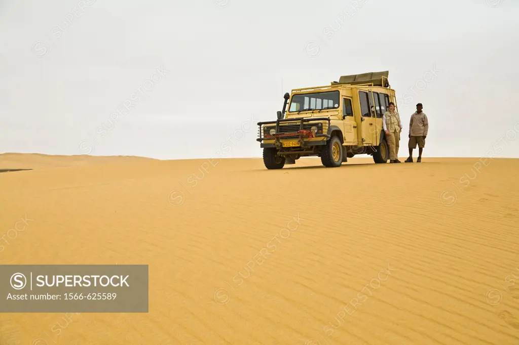 A landrover and two people in the desert of the Skeleton Coast Park, Namibia, Africa