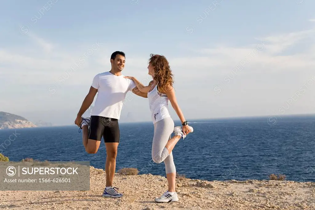 Couple stretching by the sea in a cliff in Ibiza