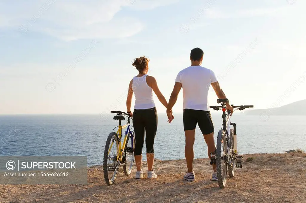 Couple enjoying the views in a cliff with their bikes