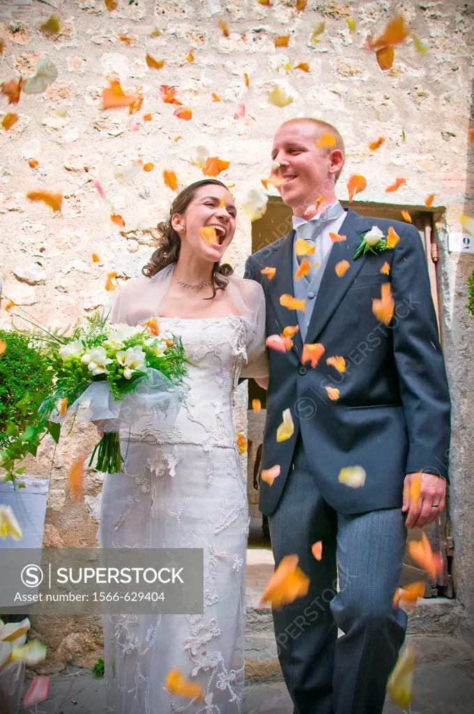 Newlyweds exiting church with flower petals. Central Italy.