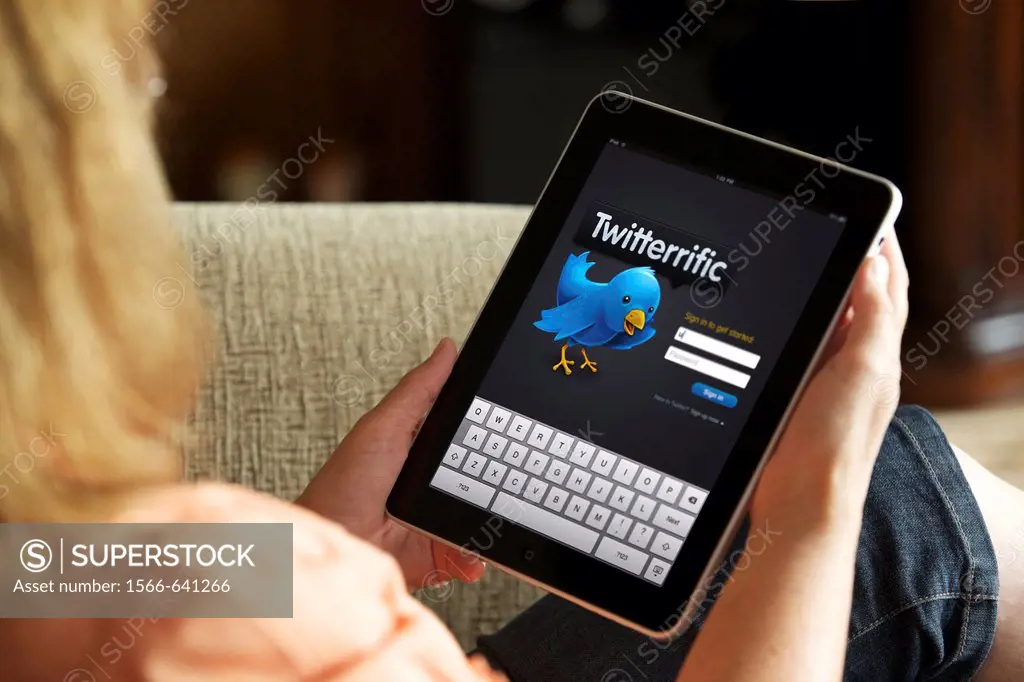 Close up of a woman hand holding an iPad showing Twitter app screen page