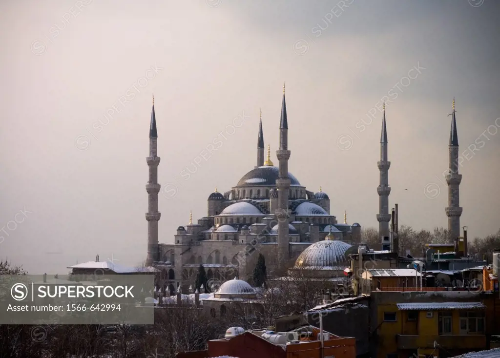 Shy sunrise in winter on the snowy Sultan Ahmed Mosque Turkish: Sultanahmet Camii also called blue mosque, Istanbul, Turkey, with the fogy Bosphorus i...