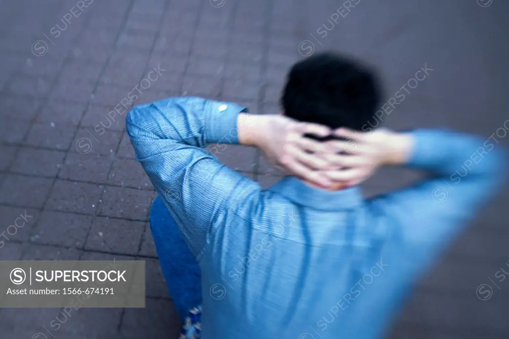 Young man sitting on a sidewalk