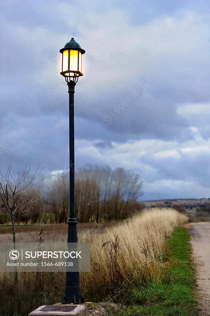 Streetlight illuminating a country road on a stormy sky
