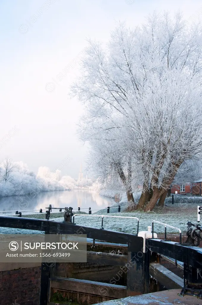 A canal lock in Worcester with a frosty river Severn in the background  England