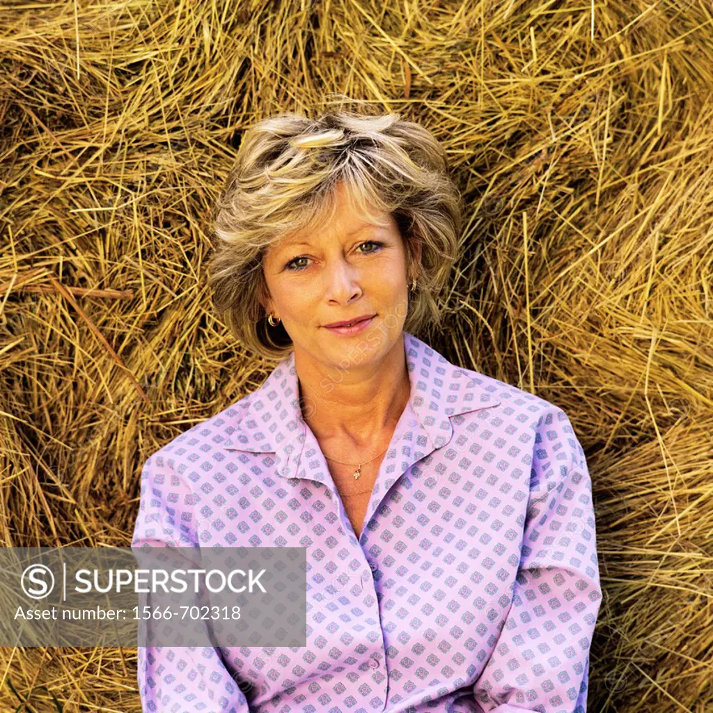 Mature woman portrait against bale of hay