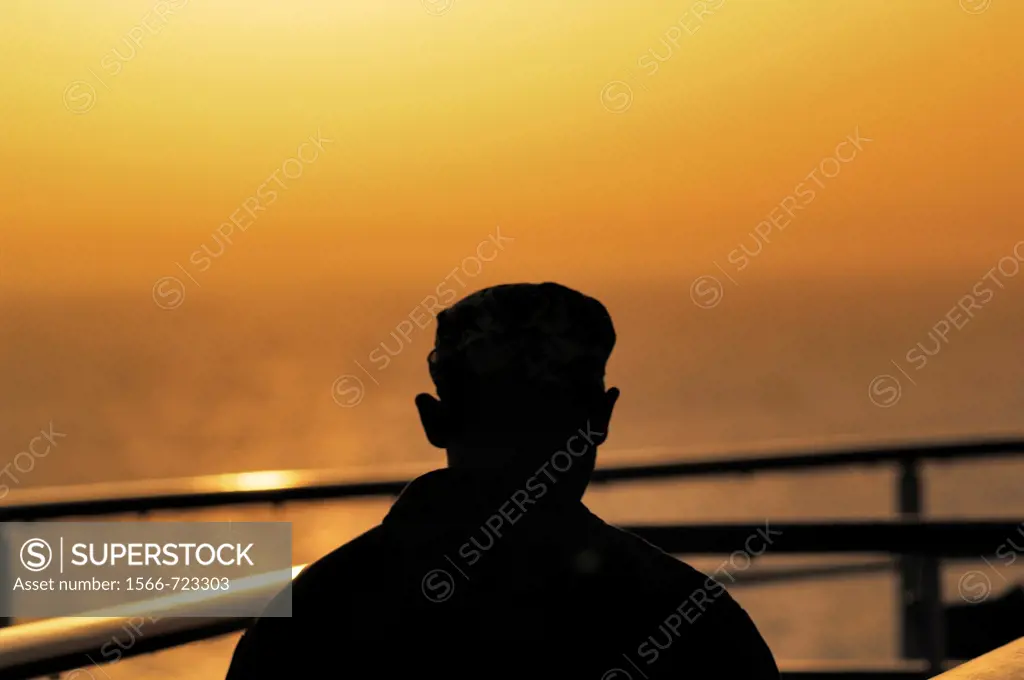 A man looks at hazy sunset over the Mediterranean