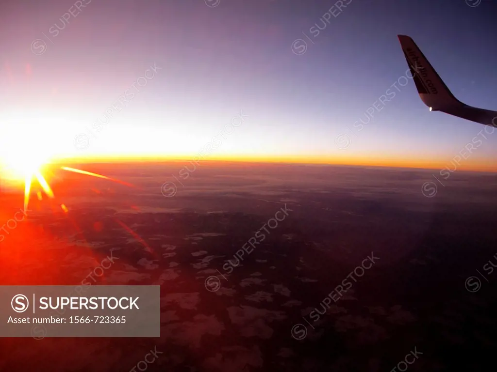 Sunrise over the clouds, wing tip position light and the rising sun