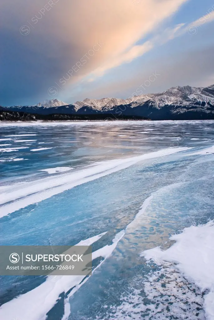Clouds glowing in a winter sunset over the wind polished ice of Abraham Lake, Alberta Canada