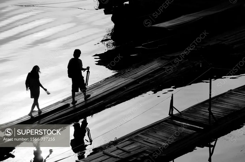Silhouette of two people, who go over a bridge