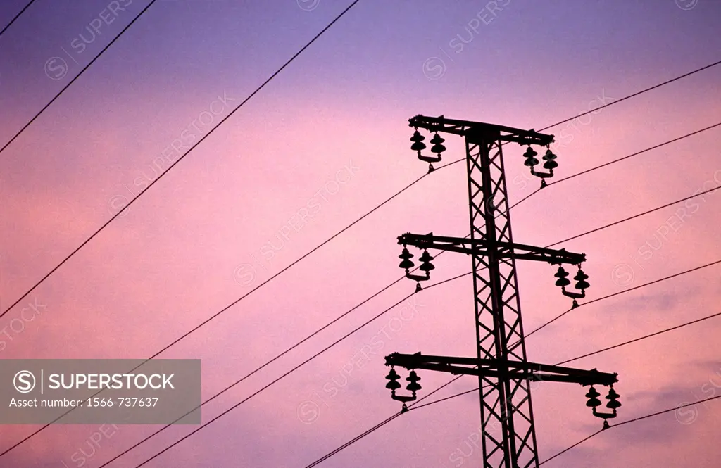 Silhouette of overland pipelines and an electricity pylon in the dusk