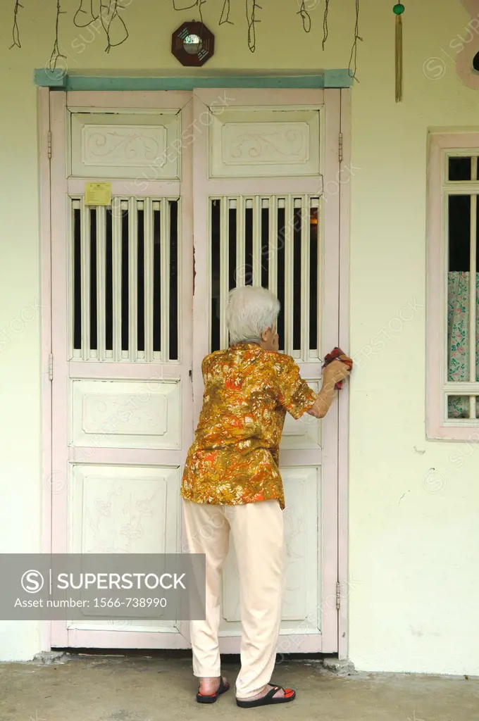 old woman cleaning her home in Chinatown in Georgetown, Penang, Malaysia