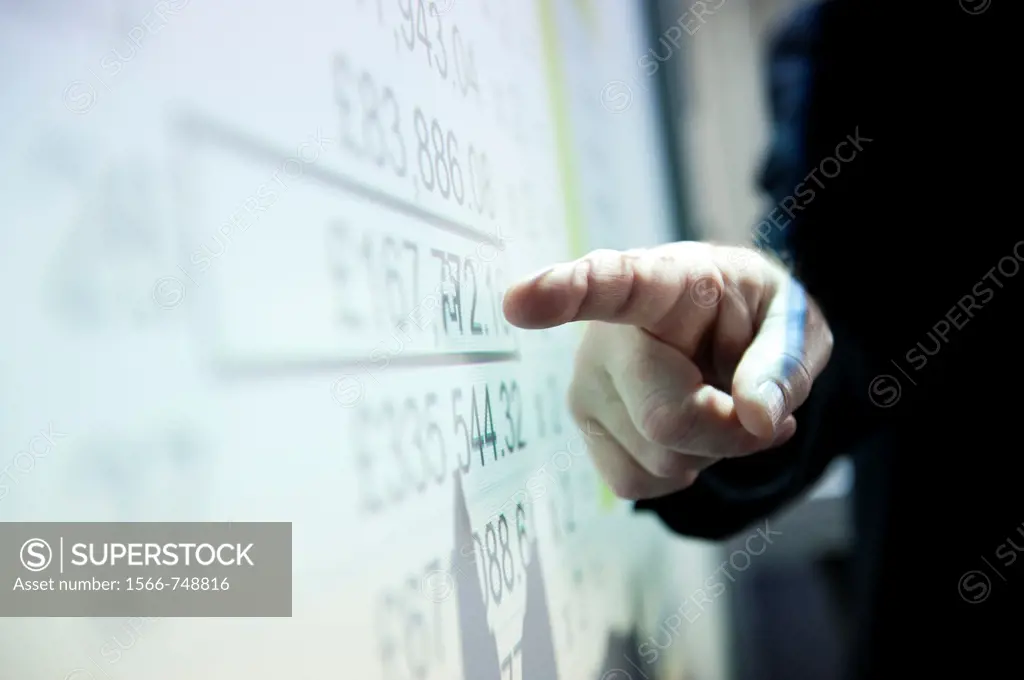 A man presenting a spreadsheet of figures on a digital whiteboard