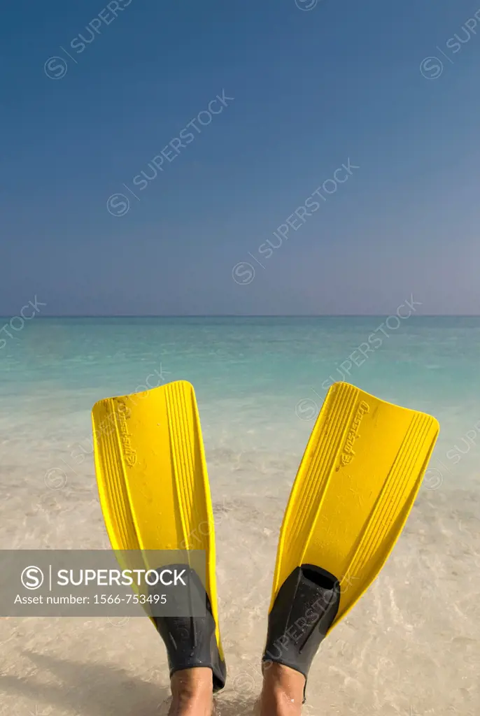 A person sitting in the ocean wearing Yellow flippers Maldives