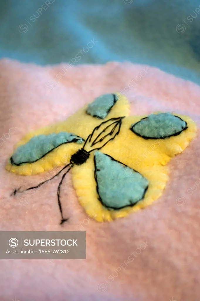 A yellow and blue butterfly appliqued on a baby quilt made of fleece