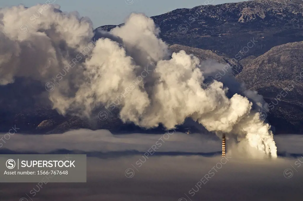 One of Megalopolis thermoelectric power plants shrouded in a mixture of fog, and smog from its own chimneys, Arcadia, central Peloponnese, Greece  The...