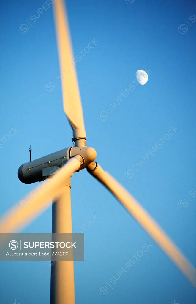Wind turbine rotors with blue sky and moon generating electricity on wind farm at Bryn Titli near Rhayader, central Wales, UK