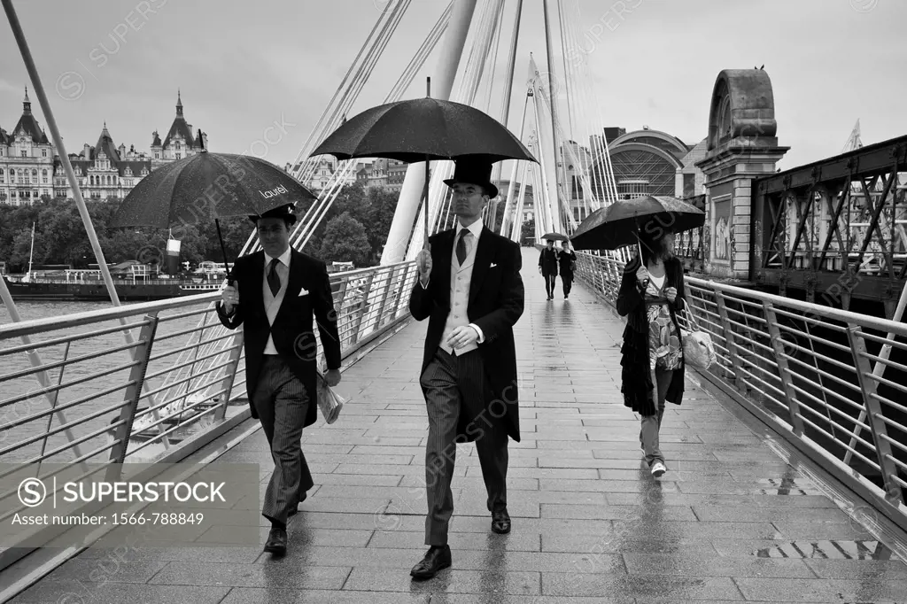 Two men dressed in suits cross Hungerford/Golden jubilee bridge on their way to Royal Ascot, London, England