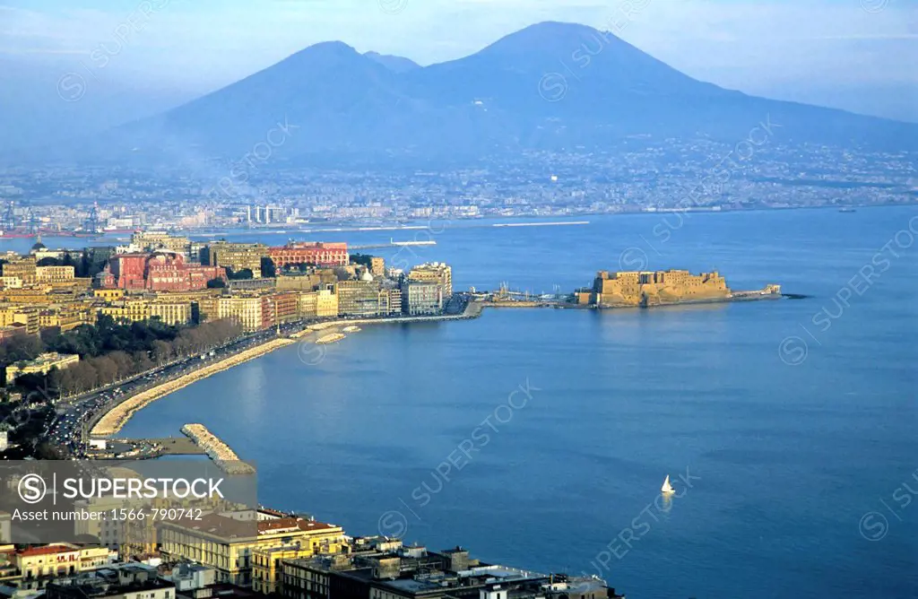 View across the Bay of Naples showing the Aragonese Castle on the peninsula of Ischia with the townscape and Mount Vesuvius in the background, Naples,...