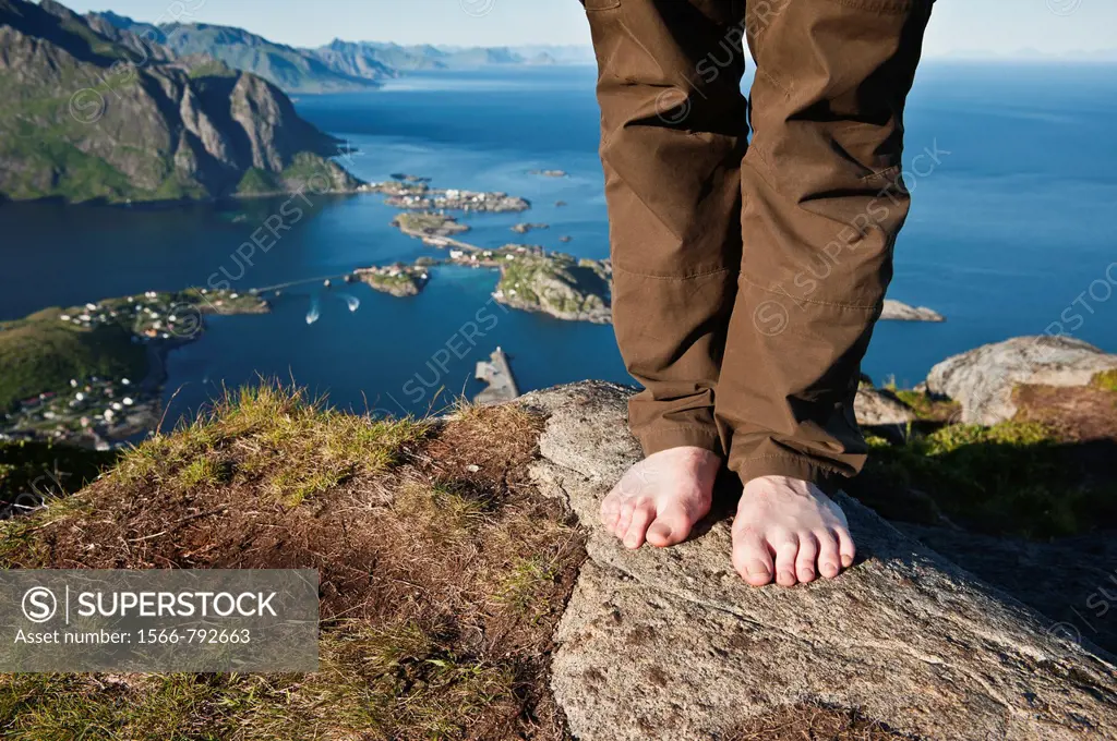 Man stands barefooted on rock on Reinebringen, Reine, Lofoten islands, Norway