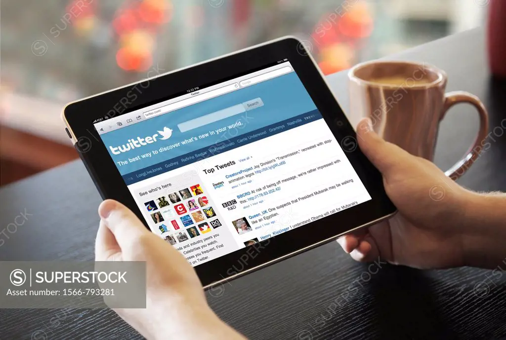 Close up view of a man handholding an iPad with Facebook screen at a cafe