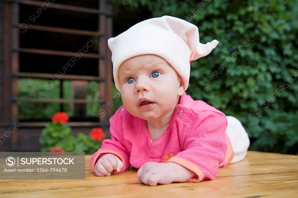 Emotional three month old baby girl on wooden table