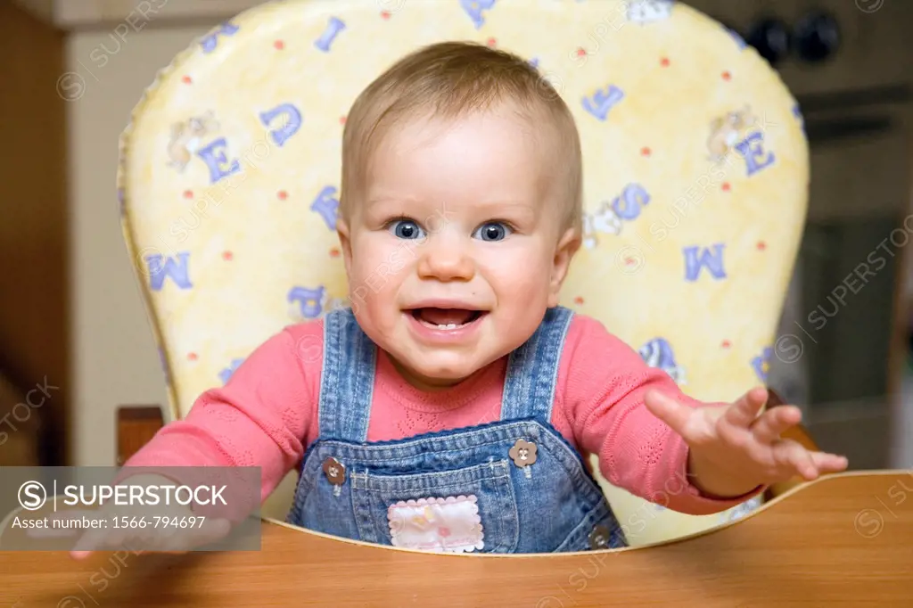 Happy Smiling Eight Month Old Infant Girl in High Chair