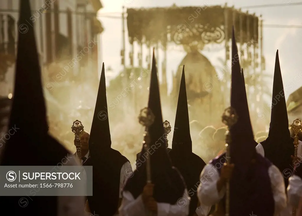 Penitents walk in front of a throne displaying a sculpture of Our Lady of Sorrows during an Easter Holy Week procession in Carmona village, Seville pr...