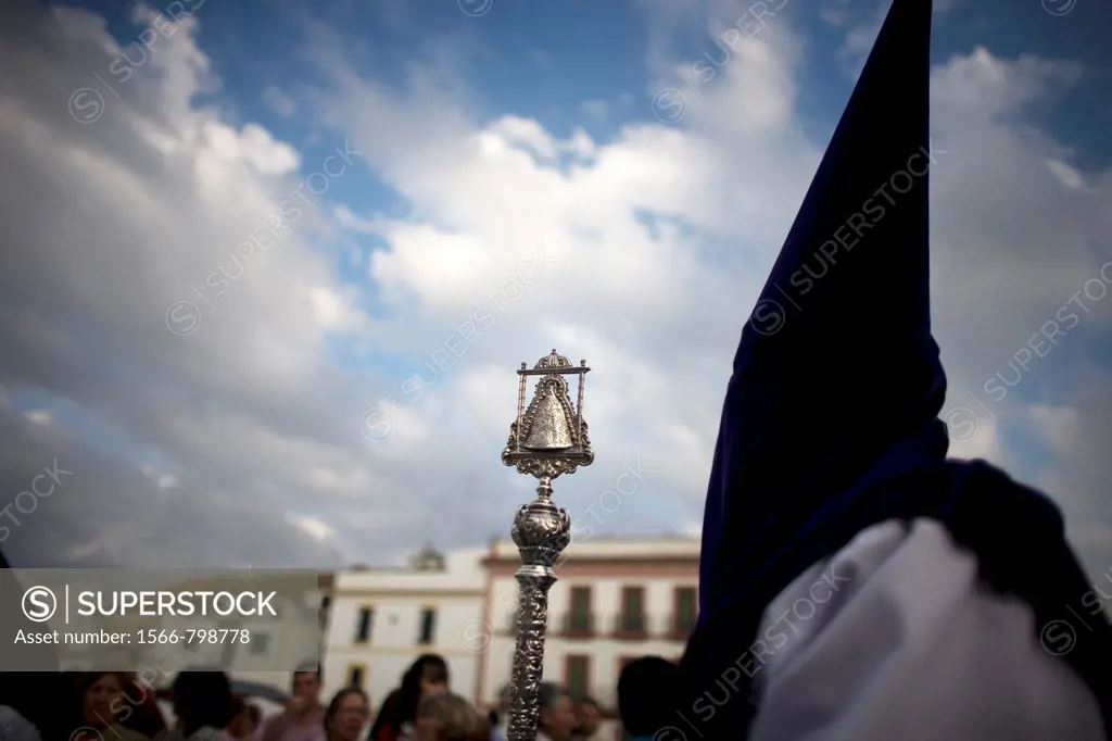 A penitent holds a metal ceremonial staff decorated with a Virgin Mary image during an Easter Holy Week procession in Carmona village, Seville provinc...