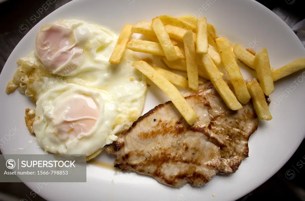 A combination plate or plato combinado with fried eggs, fried potatoes and tenderloin sit in a restaurant of Cordoba, Andalusia, Spain, april 18, 2011