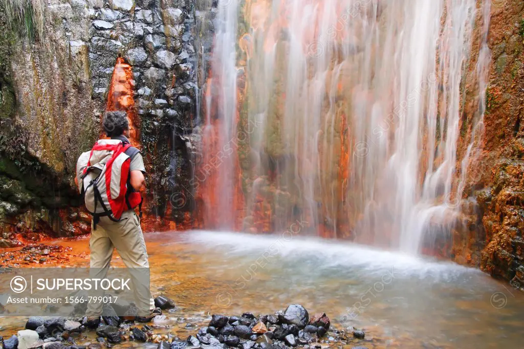 Hiker near Cascada Colorada, coloured waterfall, in El Parque Nacional de la Caldera de Taburiente on La Palma in the Canary islands