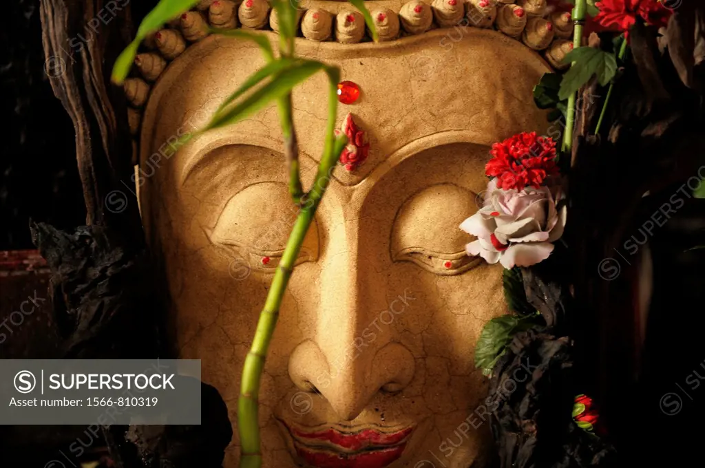 buddha stone image decorated with flowers , chinatown , bangkok, thailand