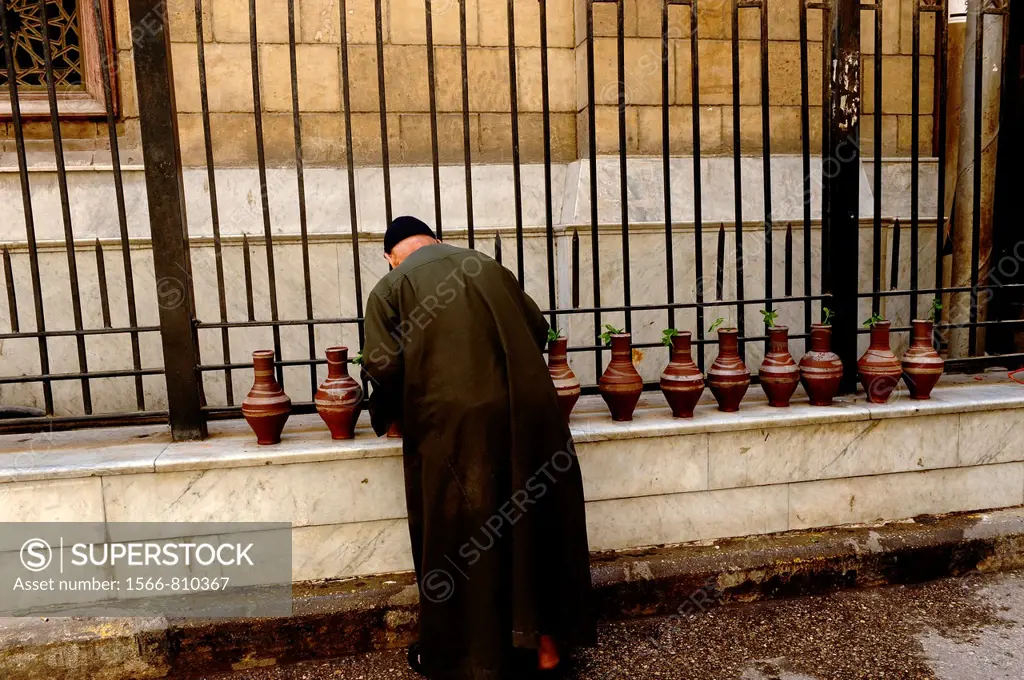 imam filling up water bottles, outside the Al-Hussein Mosque , which sits on the site of the cemetery of the Fatimid caliphs , islamic cairo, cairo, e...