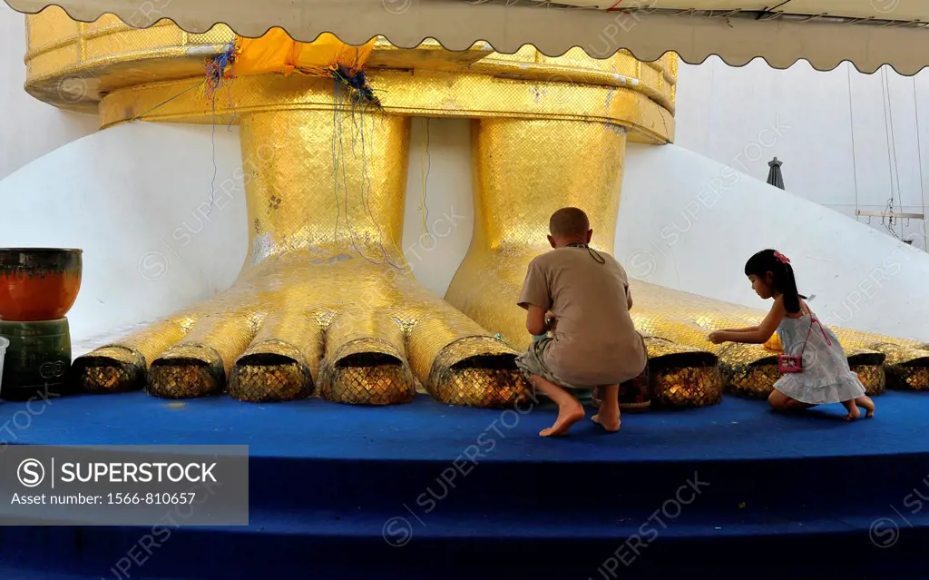 people praying at the feet of the Standing buddha knowns as luang pho at Wat Intharawihan, nakhon district of bangkok, thailand